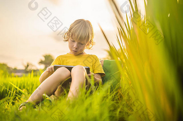 快乐孩子坐着场持有平板电脑男孩坐着草阳光明媚的一天首页学校教育玩平板电脑