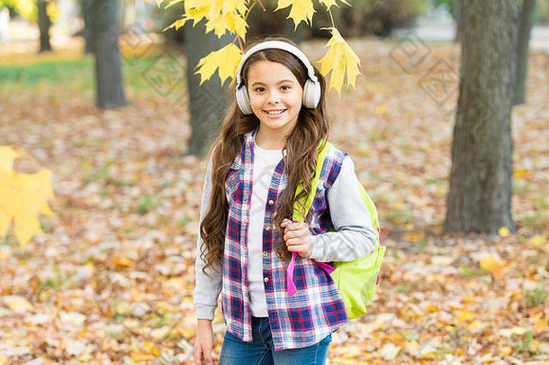 女学生听现代耳机耳机技术可爱的孩子微笑立体声耳机旋律秋天下降叶子快乐女孩穿耳机秋天自然背景
