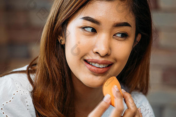 特写镜头年轻的亚洲积极的女人应用粉闪亮的脸模糊背景