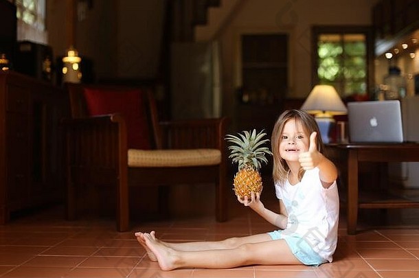 微笑女孩坐着地板上<strong>菠萝</strong>显示拇指