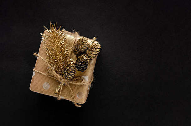 礼物盒子包装工艺纸金冷杉锥黑色的背景圣诞节假期概念复制空间开销