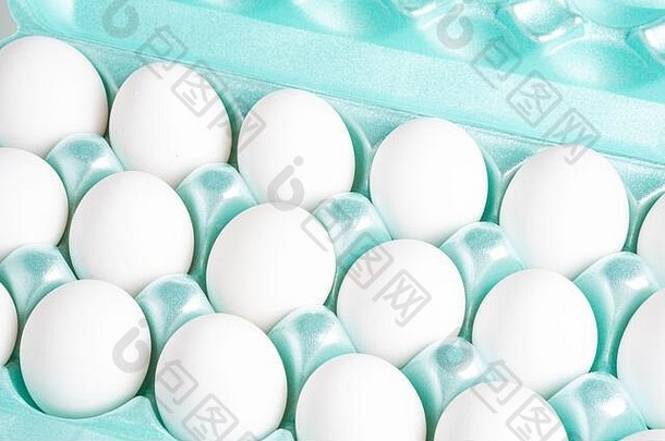 特写镜头拍摄明亮的绿色聚苯乙烯泡沫塑料箱完整的白色鸡蛋集白色背景