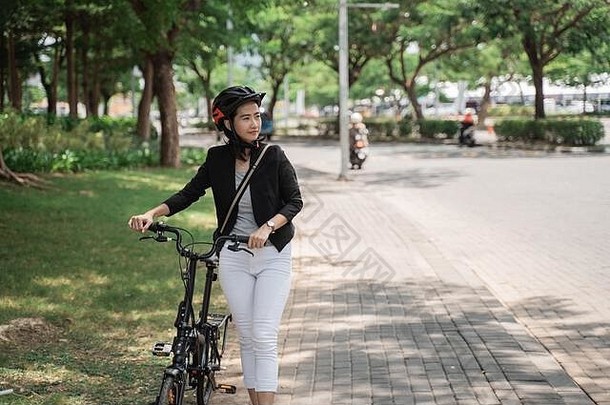 亚洲年轻的女人穿头盔工作走<strong>自行车</strong>