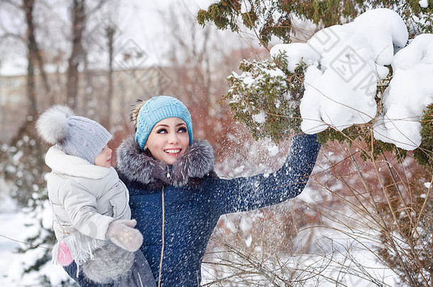 妈妈。年轻的女儿拥抱冬天公园妈妈。女儿雪带来了树快乐家庭