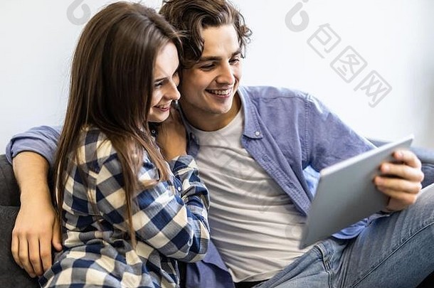 浪漫的放松年轻的夫妇平板电脑电脑沙发