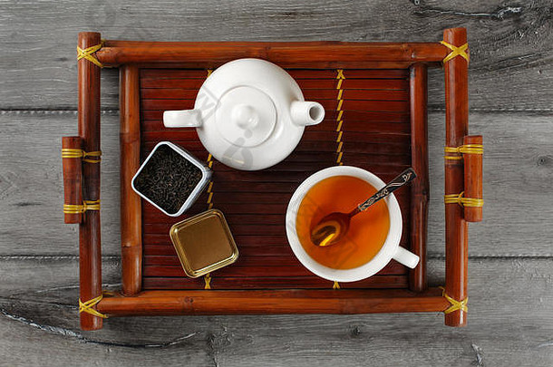 表格前视图白色陶瓷<strong>茶壶</strong>杯热黑色的茶银勺子打开剂量宽松的叶茶服务竹子托盘