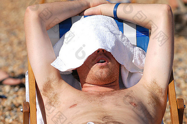 男人。“小睡”甲板椅子闷热的太阳布赖顿海滩