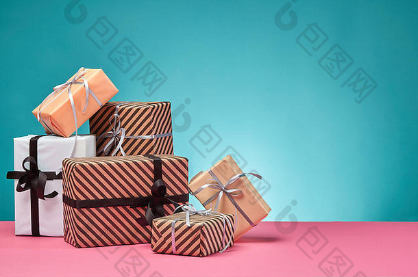 大小色彩斑斓的条纹平原纸礼物盒子系丝带弓粉红色的表面蓝色的背景特写镜头复制空间