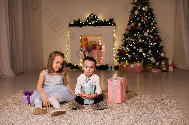 男孩女孩开放圣诞节礼物圣诞节树一年的夏娃家庭庆祝活动