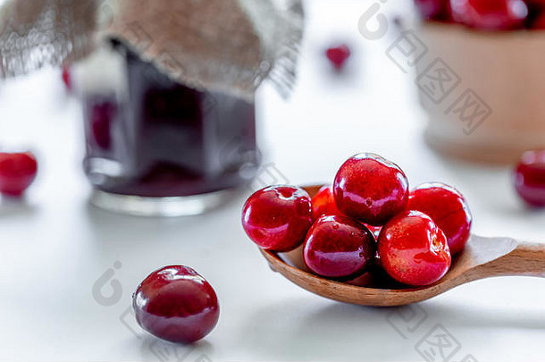 红色的成熟的樱桃小时Jar木勺子白色背景平躺食物概念