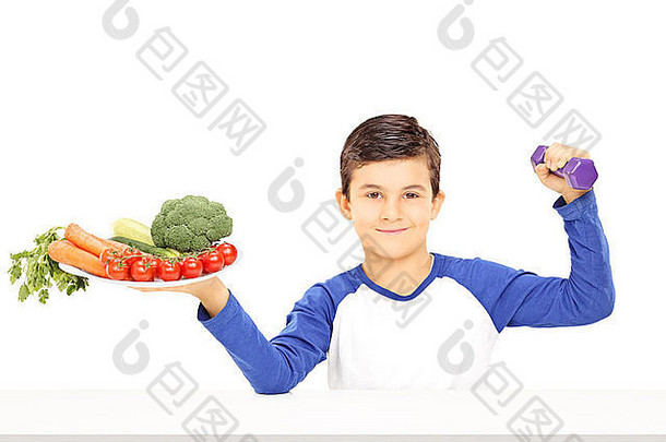 年轻的男孩持有板完整的蔬菜哑铃