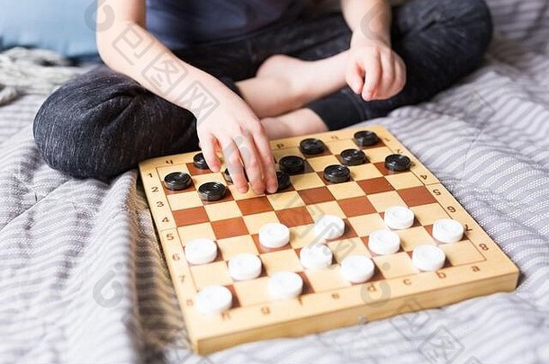 年轻的孩子手玩跳棋表格游戏床上保持首页检疫概念董事会游戏孩子们休闲概念家庭时间