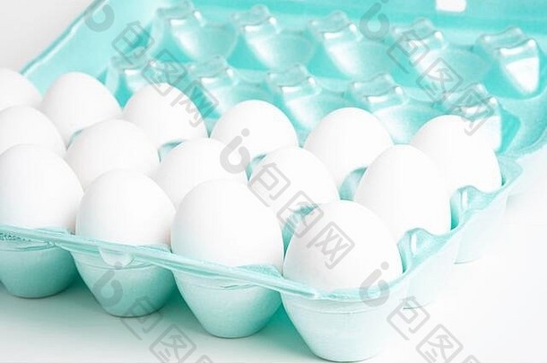 特写镜头拍摄明亮的绿色聚苯乙烯泡沫塑料箱完整的白色鸡蛋集白色背景