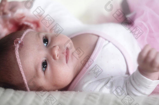 美丽的微笑新生儿婴儿女孩粉红色的衣服床上