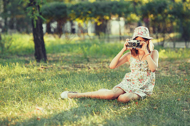 女孩玩<strong>照片</strong>相机坐着草公园自拍拍摄世界