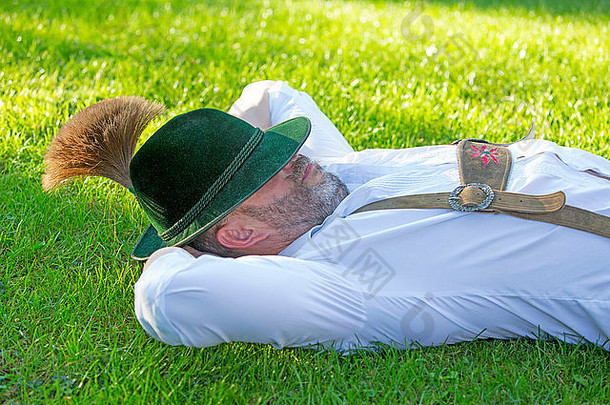 男人。传统的巴伐利亚衣服睡觉草