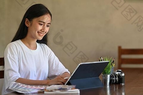照片有创意的女人写作电脑平板电脑键盘情况下手写笔笔坐着木工作桌子上古董坐着房间