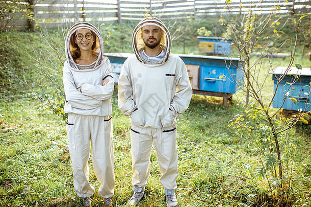 肖像男人。女人养蜂师保护统一的站小传统的养蜂场木蜂房背景