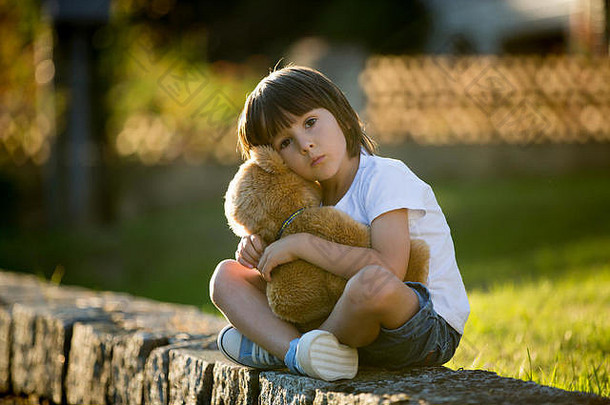 甜蜜的男孩玩泰迪熊小农村路径日落夏季