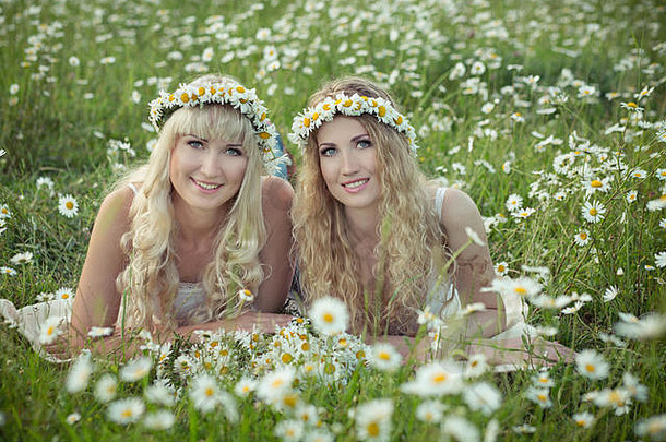 可爱的金发碧眼的年轻的姐妹女孩夫人乳白色的白色皮肤享受时间穿内衣阿纳德姆花环头草地实验。