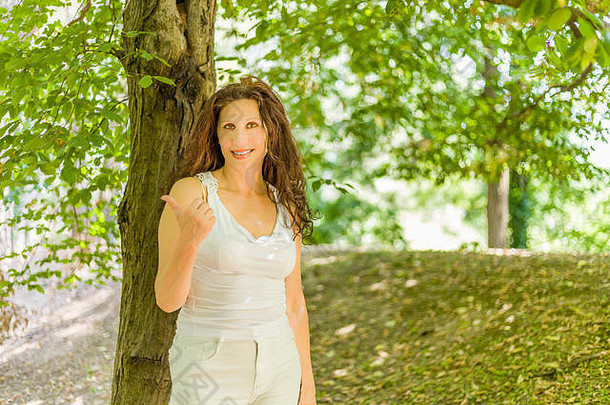 快乐的丰满的优雅的成熟的女人微笑相机显示拇指绿色花园背景复制空间