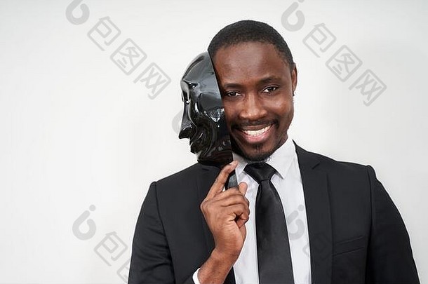 非洲年轻的男人。穿黑色的西装采取塑料面具揭示脸微笑