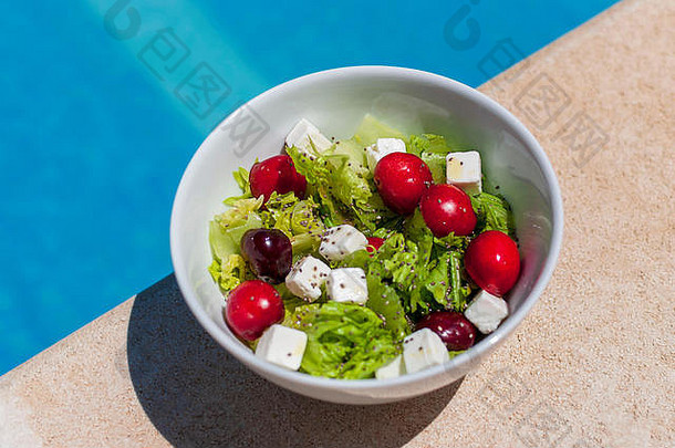新鲜的健康的沙拉孤立的白色碗一边游泳池阳光明媚的一天生菜种子大红色的多汁的樱桃羊