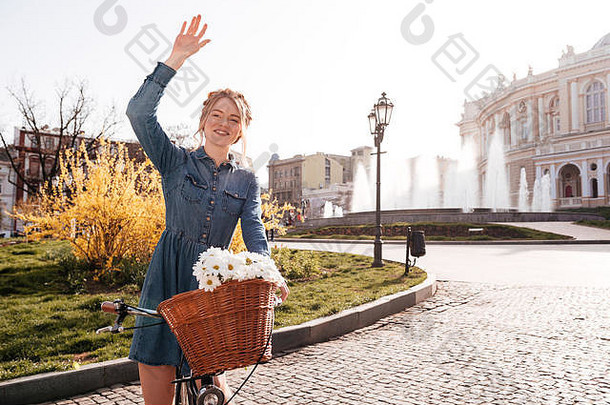 快乐的可爱的年轻的女人自行车站挥舞着手街