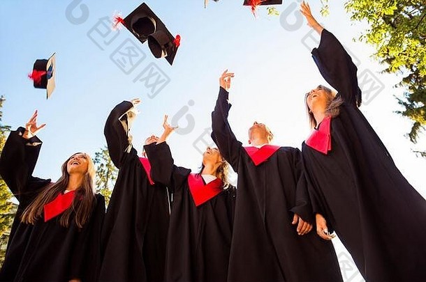 成功的学生祝贺你扔毕业帽子空气庆祝