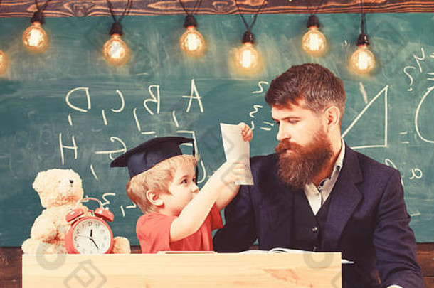 忙孩子研究学校老师父亲检查家庭作业帮助男孩儿子个人研究概念老师正式的穿学生学位帽教室黑板背景