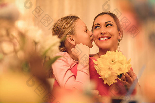 可爱的女孩给妈妈。花束黄色的水仙花接吻