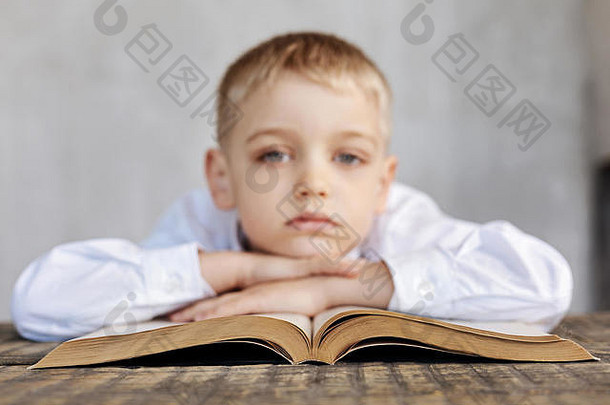 疲惫的年轻的男孩无聊阅读
