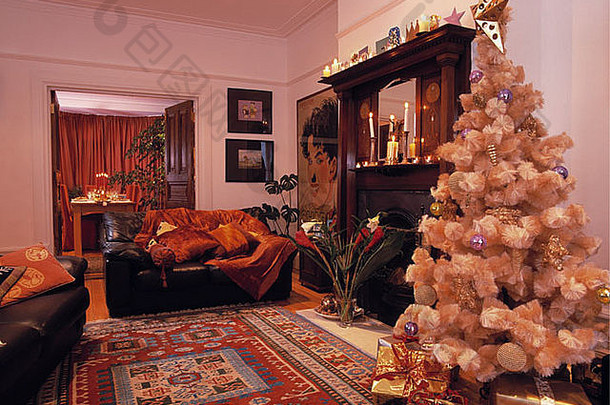 黄金人工圣诞节树生活房间有图案的地毯黑色的皮革沙发