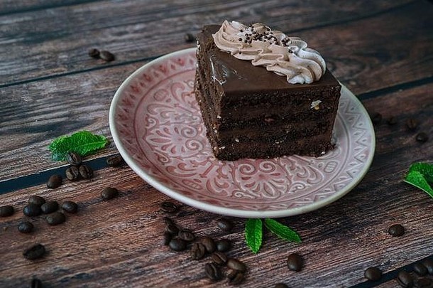 一块巧克力蛋糕奶油板巧克力蛋糕木背景咖啡豆子薄荷叶子美味的片分层蛋挞板烘焙<strong>装修</strong>巧克力蛋糕