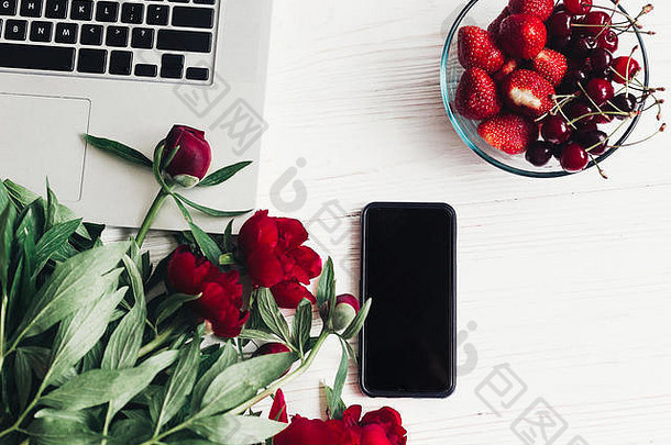 时尚的移动PC电话草莓樱桃美丽的红色的牡丹白色木背景平躺空间文本快乐女人的一天