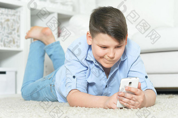 肖像年轻的男孩智能手机玩游戏首页