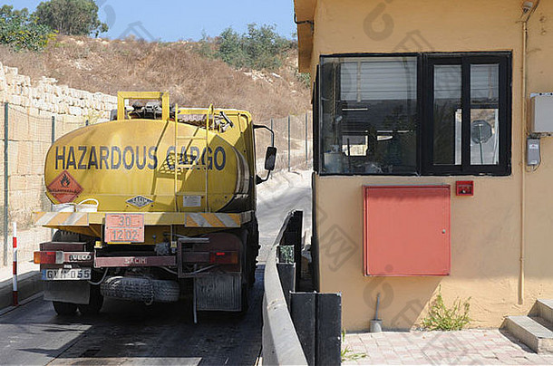 黄色的卡车携带危险货物通过垃圾填埋场入口