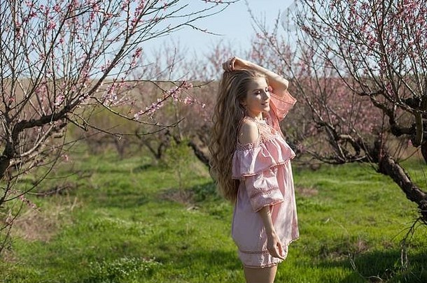 美丽的金发女郎女人粉红色的衣服走开花花园春天