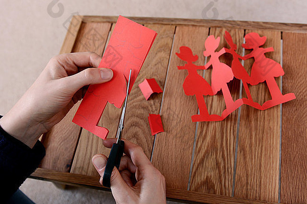 特写镜头女人切割链红色的纸娃娃剪刀