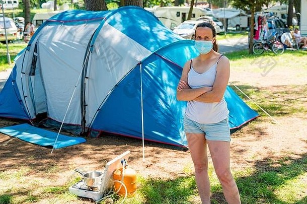 女人穿医疗面具站前面野营帐篷度假胜地