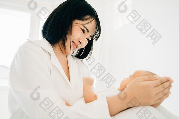 快乐的有爱心的年轻的亚洲女白色穿持有婴儿婴儿首页