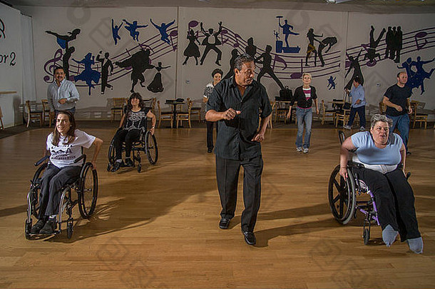 非洲美国跳舞老师指示残疾成年人执行轮椅跳舞正常的成年人三迭戈