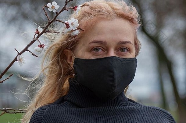 美丽的年轻的欧洲女人春天衣服街医疗脸面具冠状病毒科维德