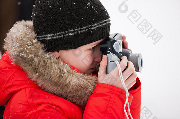 可爱的男孩红色的派克大衣夹克在户外美丽的冬天雪一天采取照片小相机