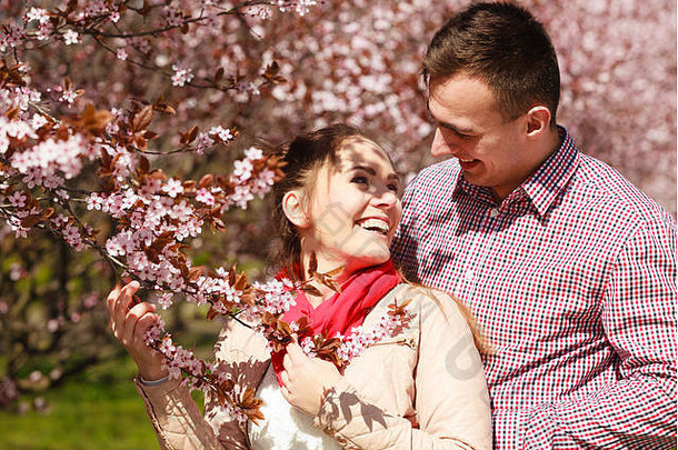 约会年轻的女人男人。走夫妇爱放松开花樱桃树公园阳光明媚的春天一天