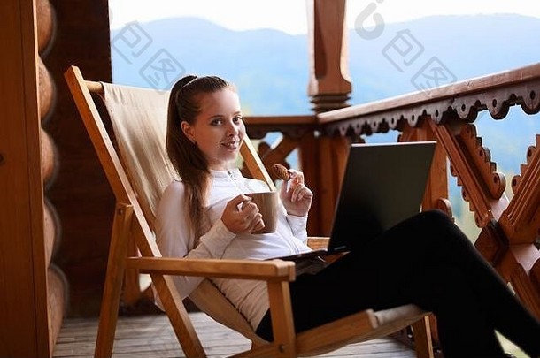 年轻的有吸引力的业务女人工作移动PC山度假胜地杯茶饼干女放松甲板椅子笔记本
