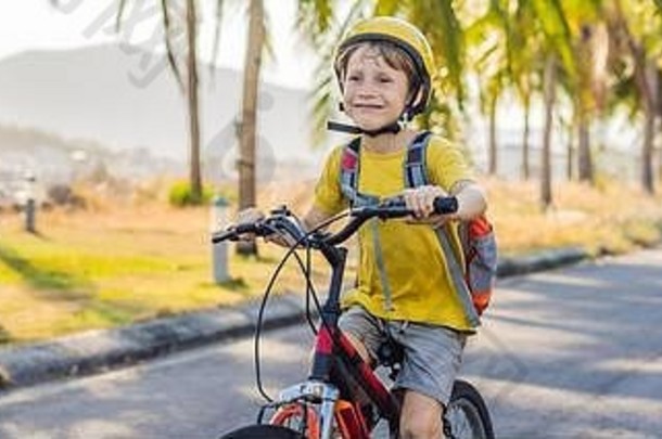 活跃的学校孩子男孩安全头盔骑自行车背包阳光明媚的一天快乐孩子骑自行车学校安全孩子们在户外