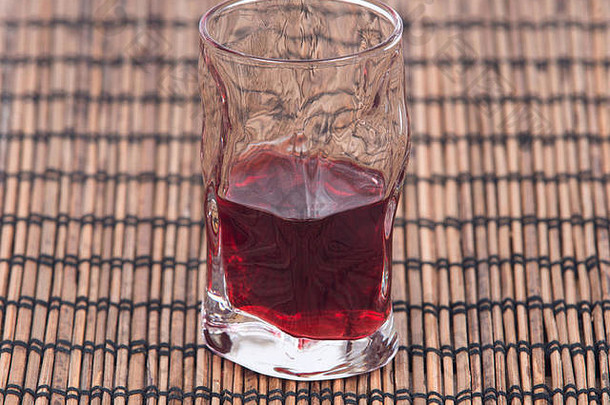 自制的树莓利口酒拍摄玻璃孤立的竹子盘垫纸