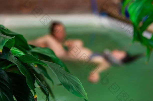 特写镜头新鲜的绿色植物叶子阿卡治疗中<strong>心怀</strong>孕了女人游泳池接收阿卡治疗专业治疗师