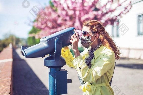 年轻的红色头发的人旅游女人面具看双筒望远镜公园流感大流行